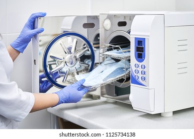Sterilizing medical instruments in autoclave. Dental office. Dentist assistant's hands get out sterilizing medical instruments from autoclave. Selective focus
 - Shutterstock ID 1125734138