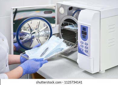Sterilizing medical instruments in autoclave. Dental office. Dentist assistant's hands get out sterilizing medical instruments from autoclave. Selective focus
 - Shutterstock ID 1125734141