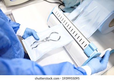 Sterilizing medical instruments in autoclave. Dental office.Close up dentist assistant's hands holding packaged with vacuum packing machine medical instruments ready for sterilizing in autoclave.