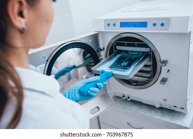 Sterilizing medical instruments in autoclave. Dental office - Shutterstock ID 703967875