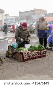 STERLITAMAK - RUSSIA 9TH APRIL 2016 - Russian market trader reads a book as she waits for customers to buy her dill and parsley herbs and spring onions at a stall in Sterlitamak, Russia in April 2016.