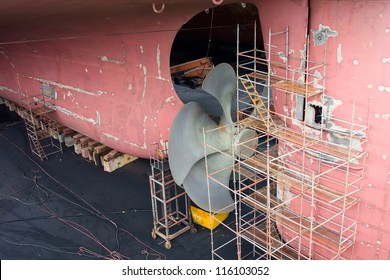 The Stern Of The Container Ship On Dry Dock. Propeller And Rudder Maintenance.