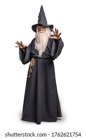 A stern grey-haired bearded wizard in a gray cassock and a cap is practicing sorcery and doing magic against a white insulating background. - Shutterstock ID 1762621754