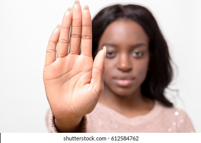 Stern Young African Woman Making A Halt Or Stop Gesture Raising The Palm Of Her Hand With A Determined Stare Isolated On White