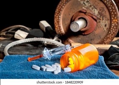 Steroid Medication Including Pills And A Syringe In Front Of Exercise Equipment.  Image Can Be Used For Steroid And Performancing Enhancement Inferences In Sports.