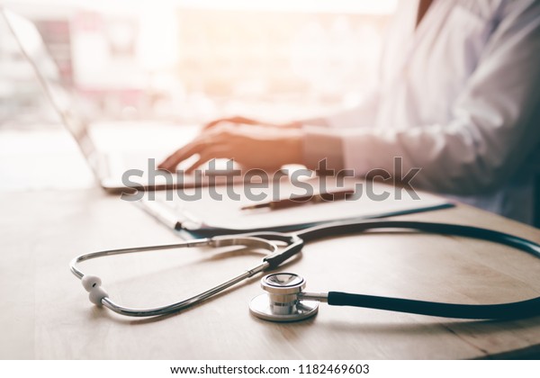 Stethoscope and background\
doctor using laptop at desk in clinic working on computer at room\
office.