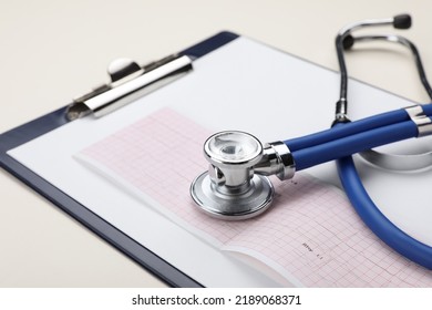 Stethoscope, Clipboard And Cardiogram Paper On Beige Background, Closeup