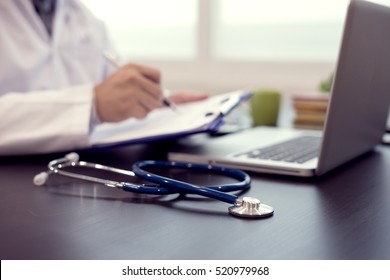 Stethoscope with clipboard and Laptop on desk,Doctor working in hospital writing a prescription, Healthcare and medical concept,test results in background,vintage color,selective focus - Shutterstock ID 520979968
