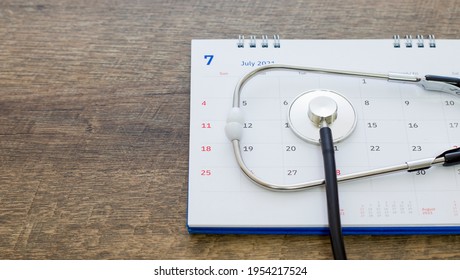 Stethoscope with date on a calendar page on a wooden floor. Healthcare concept.