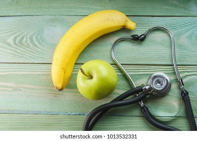 Stethoscope, green apple, banana on a wooden blue background, top view - Powered by Shutterstock