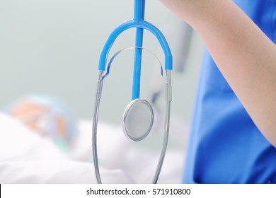 Stethoscope In Hand Of Doctor At The Bedside.