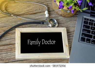 Stethoscope, laptop and flower on wooden table with FAMILY DOCTOR word as medical concept