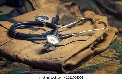 Stethoscope Lies On The Uniform Of A US Soldier. The Concept Of Health Care, Military Insurance, State Care. Top View. Mixed Media