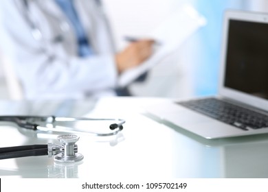 Stethoscope Lying On Glass Desk With Laptop Computer At Busy Physician Background. Medicine Or Pharmacy Concept. Medical Tools At Doctor Working Table