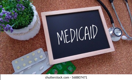 Stethoscope, Medicine, Chalk Board And Flower With Inscription Medicaid On A Wooden Table. Medical And Health Care Concept.

