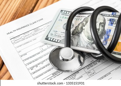 Stethoscope With Money And Health Insurance Claim Form On The Table. 