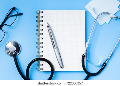 Stethoscope, notebook, glasses and pen on a blue table, concept of health and medicine