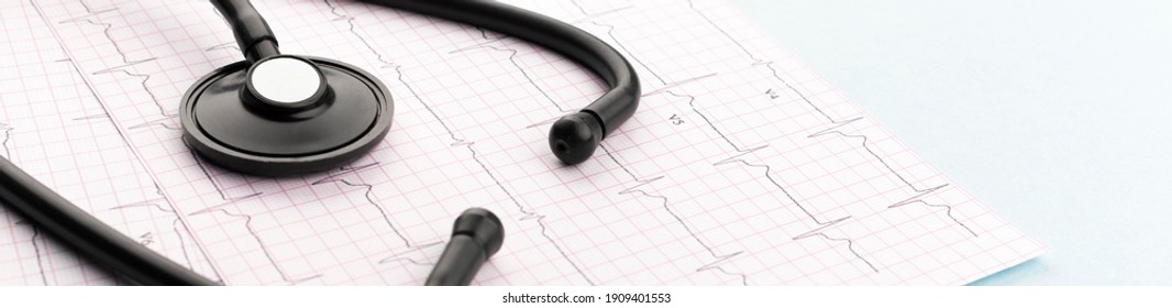 Stethoscope on cardiogram on blue background, wide angle view. Cardiology concept. Panoramic web banner.