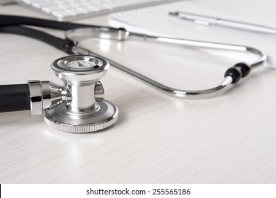 Stethoscope on doctor's desk with keyboard and pad