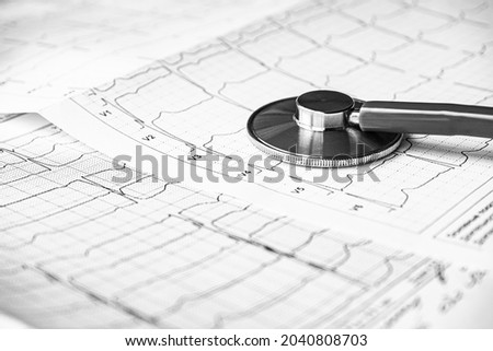 Stethoscope on the electrocardiogram (ECG) graph (top view). EKG printout with stethoscope. Medical health concept. Auscultation, listening to the heart pulse with a stethoscope