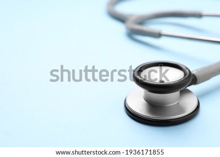 Stethoscope on light blue background, closeup. Space for text