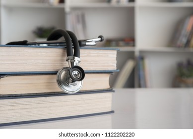 Stethoscope On Stack Of Medical Books On Doctor Desk At Room In Hospital.