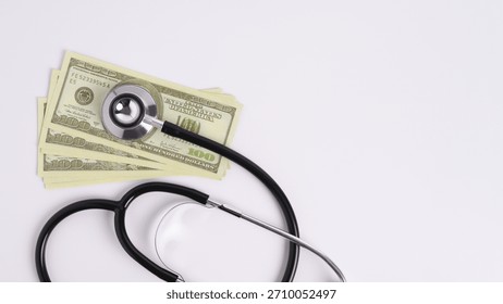 Stethoscope on stack of US dollar bills isolated on white background, representing expensive healthcare costs and medical insurance concepts.