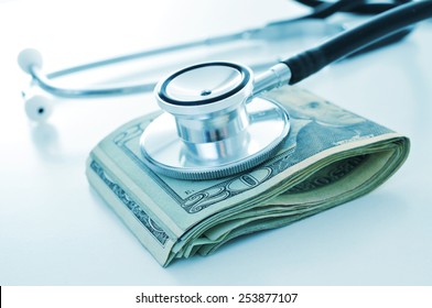A Stethoscope On A Wad Of US Dollar Bills, Depicting The Concepts Of The Health Care Industry Or The Health Care Costs
