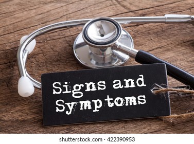 Stethoscope on wood with Signs and Symptoms words as medical concept