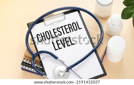 Stethoscope and paper note with text CHOLESTEROL LEVEL. Health concept.
