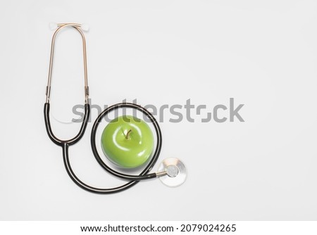 Stethoscope or phonendoscope with fresh green apple on white background with place for the text, top view: health and Medical concept, proper nutrition