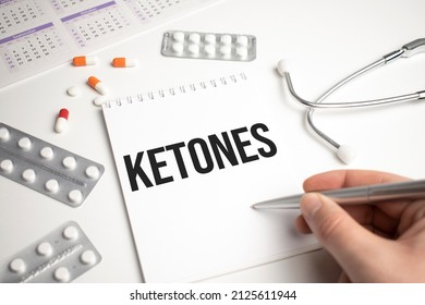 Stethoscope, pills and notebook with KETONES word on medical desk.