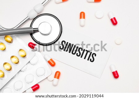 Stethoscope, pills and notebook with Sinusitis word on medical desk.