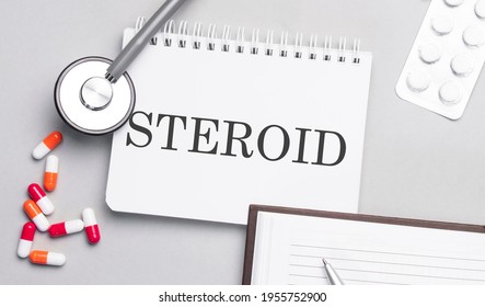 Stethoscope, Pills And Notebook With STEROID Text On The Medical Table.