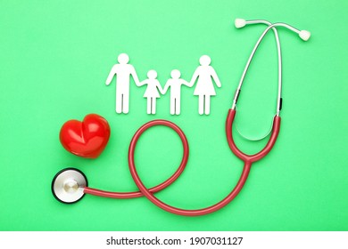 Stethoskop mit rotem Herz und Familienfigur auf grünem Hintergrund