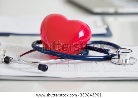 Stethoscope and red heart lying on cardiogram. Healthcare, cardiology and mediacal concept