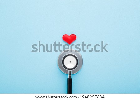 Stethoscope with red heart on light blue table background. Pastel color. Doctor tool for heartbeat listening. Healthcare concept. Closeup.