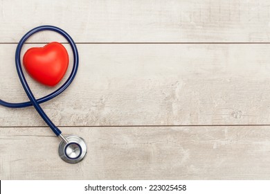 Stethoscope with red heart on a wood background