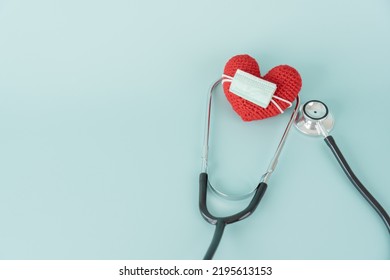 Stethoscope And Red Heart Shape And Face Mask Concept Of Health Care And Medical. Protect Heart With Surgical Mask Doctor And Hospital Equipment On Light Blue Background.