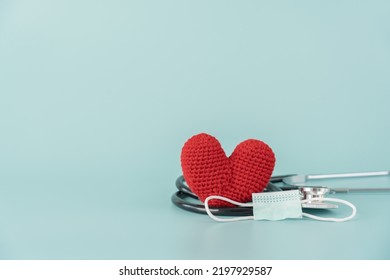 Stethoscope And Red Heart Shape And Face Mask Concept Of Health Care And Medical. Protect Heart With Surgical Mask Doctor And Hospital Equipment On Light Blue Background.