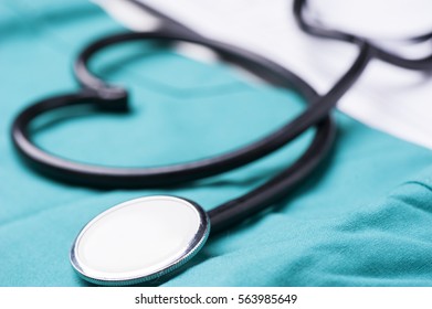  A stethoscope shaping a heart and a clipboard on a medical uniform, closeup
