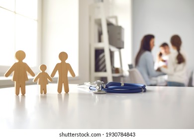Stethoscope with small wooden family member figures standing on doctor's table at clinic or hospital. Concept of medicine, family health care and regular checkup. Blurred background for medical text