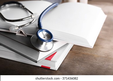 Stethoscope With Stack Of Books On Wooden Background. Medical Literature Concept