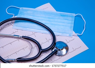 Stethoscope, Surgical Mask And ECG Strip Concept On Blue Background.