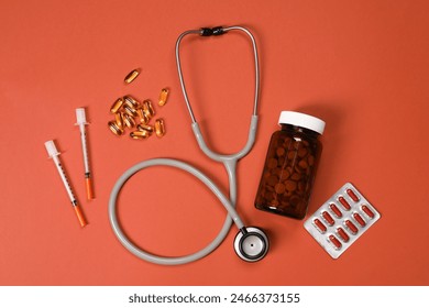 Стоковая фотография: Stethoscope, syringes and pills on crimson background, flat lay. Medical tools
