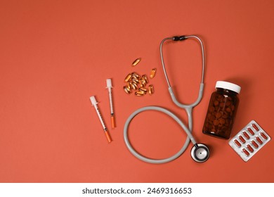 Stethoscope, syringes and pills on crimson background, flat lay. Space for text Stock fotografie