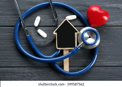 Stethoscope and tag in shape of house on wooden background - Powered by Shutterstock