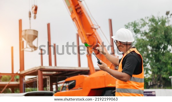 Stevedore, foreman or crane driver by walkie talkie\
for lifting safety in loading the goods or shipment, lifting by\
crane in sun light