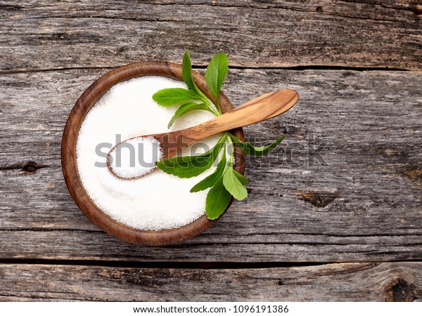 Stevia rebaudiana, sweet leaf sugar\
substitute in wooden  bowl on wooden\
background.\
