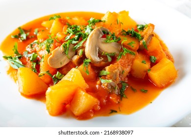 Stew made from potatoes, mushrroms and herbs boiled in tomato sauce - close up view